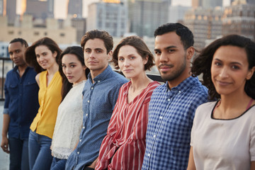 Portrait Of Friends Gathered On Rooftop Terrace For Party With City Skyline In Background