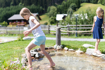 Ein 9 jähriges Mädchen betreibt wassertreten an einem natürlichen Kneippbecken