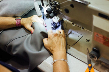 Female worker sews a piece of leather