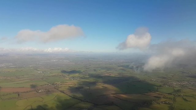 Aeroplane Descending Through Clouds in the Vale of Glamorgan, Wales Against a Blue Sky over Green Fields.