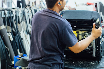 Man upholstering a car seat in leather
