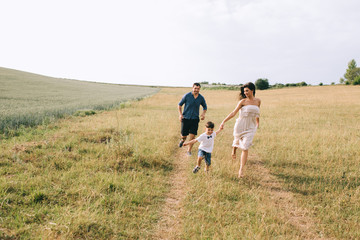 Naklejka premium parents and son running on path in field
