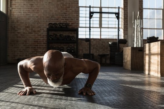 Senior man doing push ups in the fitness studio