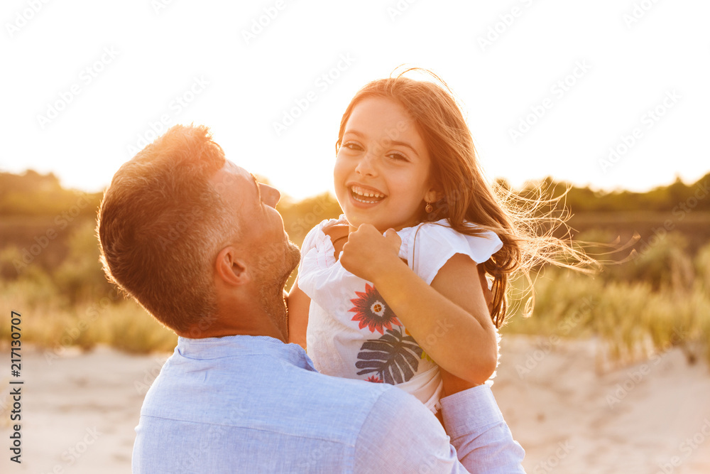 Wall mural cute family having fun together outdoors at the beach.