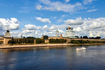 Fototapeta na wymiar View of the river Church and ancient fortress. Kremlin in Pskov, Russia. Ancient fortress. The Golden dome of the Trinity Church. Beautiful blue sky with clouds.