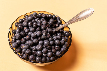 blueberries in a glass plate on an orange background