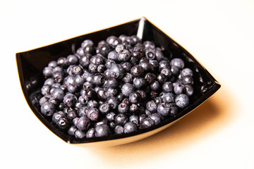 blueberries in a glass plate on an orange background