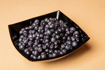 blueberries in a glass plate on an orange background