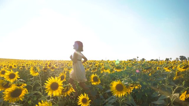 Happy little girl running happy free across the field with sunflowers. slow motion video . smelling big sunflower on summer field. Delight of a pleasant smell. Summer holiday lifestyle. concept