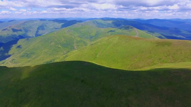 Aerial shot of colorful ranges with downy clouds in the Carpathians in summer