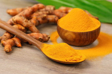 Turmeric powder in wooden bowl  and fresh turmeric on old wooden table. Indian Spices