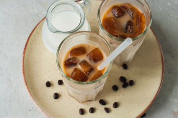 Iced coffee in a tall glass served on a plate on a white background. Overhead view.