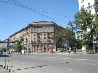 multi-storey building of a triangular shape at the intersection of two streets against the blue sky