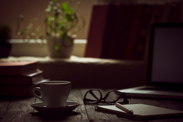 A cup of coffee in the workplace on a wooden table.