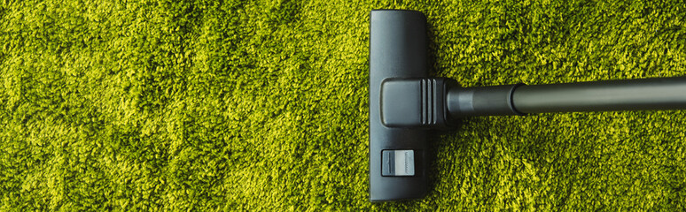 top view of cleaning green carpet with professional vacuum cleaner