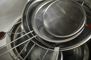 set of metal black pans and pots and colander on kitchen