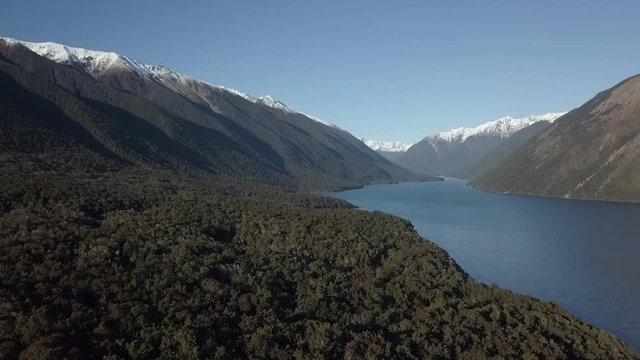 Snow covered mountain range above a native New Zealand forest and Lake. Filmed at the St Arnaud Range, Lake Rotoiti.