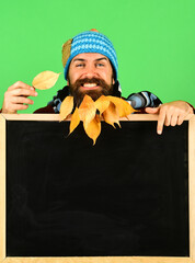 Man in hat holds blackboard and leaf on green background