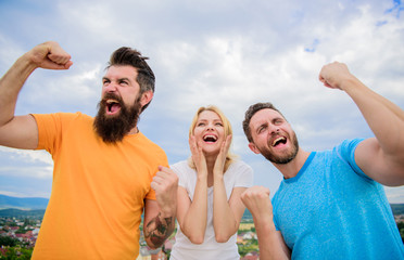 Unbelievable luck. Emotional explosion. Threesome winners happy with raised fists. We are winners. Woman and men look emotional successful celebrate victory sky background. Behavior successful team