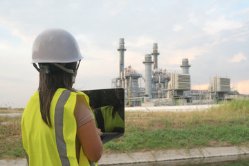 Engineering women are checking oil refineries and gas stations on notebooks. In the industrial area.
