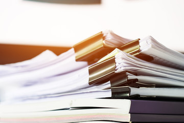 Unfinished documents stacks of paper files on office desk for report papers, piles of unfinish sheet achieves with black clips. Document is written presented. Business offices busy concept.