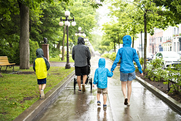 Family with childs walk on rainy day with raincoat