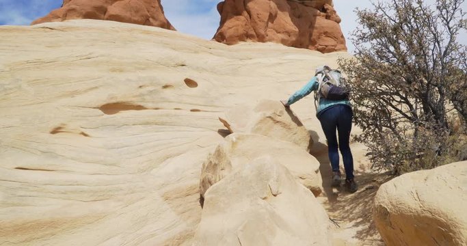 Active elderly lady backpacking outdoors and hiking up rock formation
