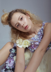 Studio portrait of blooming gorgeous lady in dress of flowers. Tired mood. Fashion concept