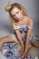 Obraz na płótnie Canvas Beautiful young woman is dressed in a avant garde long dress from flowers. Fashion Studio Portrait