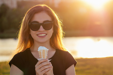 happy californian beautiful woman in sunflasses eat ice cream in a waffle horn cone at sunset on the beach. cool photosession photoshoot of girl on summer park