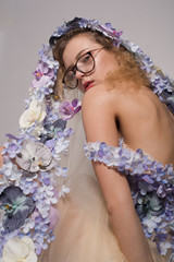 Pretty girl with glasses and with orchids on head on white background. Fashion Beauty Concept