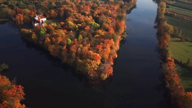 AERIAL zoom out of Castle. Flight over beautiful castle; located in landscape park with green trees forests in autumn. 4K