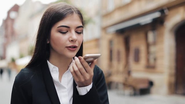 Young businesswoman using mobile phone near business center. Woman using mobile phone for business communication voice message. Concept: new business, communication, banker, call, voice translator