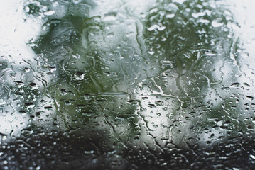 Rain drops on car front window in dark green tone, lonely and abstract water background