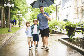 Father and child on a rainy day in a park with umbrella