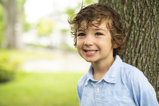 Cute Caucasian boy happily close to a tree