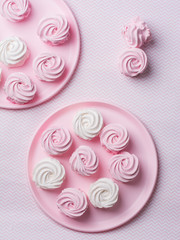 Homemade pink and white zephyr on pink plate with copy space on geometry pink table. Marshmallow, Meringue, Zephyr. Valentine's or Mothers Day. Flat lay, top view.