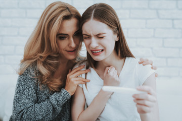 Mother near Upset Daughter with Pregnancy Test.