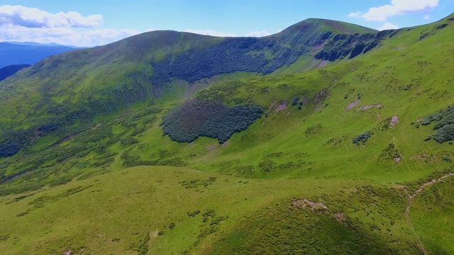 Aerial shot of a wild green ravine and high peaks in the Carpathians in summer