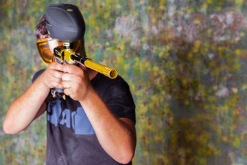 Paintball player in t-shirt shooting target with gun on