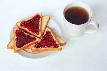 Toast with raspberry jam and cup of tea on a white background - 217143913