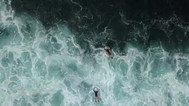 Two surfers paddling away from the shore break.