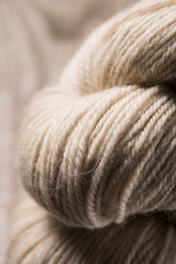 selective focus of beige knitted woolen yarn ball on wooden background