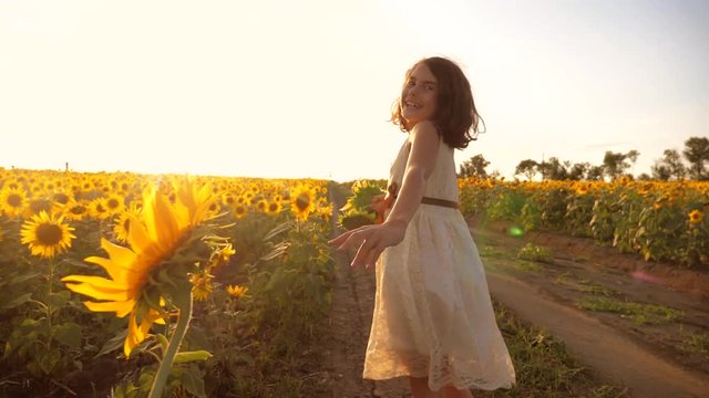 little girl running across the field with sunflowers at sunset. slow motion video. girl runner in the field lifestyle at sunset sunflowers. girl sunlight runs the concept of sunflowers