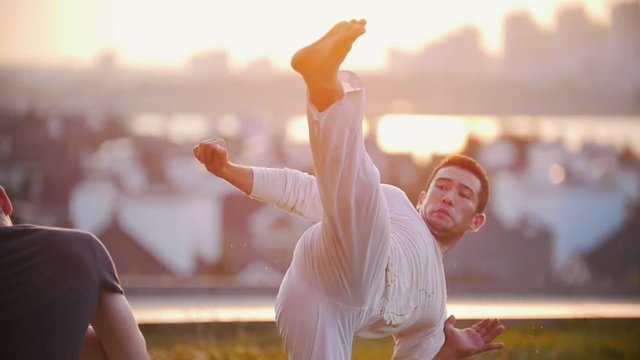 Two men with a sports physique staged a fight against the beautiful view of the city and the summer sunset