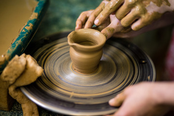 Sculpts in clay pot closeup. Modeling clay close-up. Caucasian man making vessel daytime of white clay in fast moving circle. Art, creativity. Ukraine, cultural traditions. Hobbies