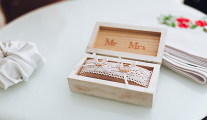 Two golden wedding rings in a wooden box on a soft pillow. Choosing wedding rings. Preparation for the ceremony.