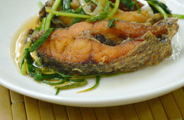 deep fried Nile Tilapia or mango fish slice dressing soy sauce and spring onion on plate