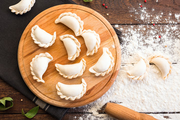 Pelmeni cooking on a board and wooden background, national Russian cuisine, vareniki