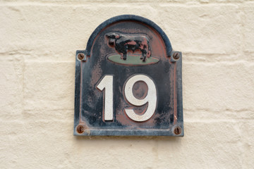 House number 19 sign with cow on wall